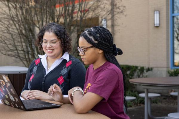 Female students working on laptop outside